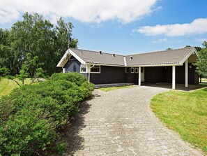 A two-story house with a covered patio, a paved driveway, and a well-maintained lawn.