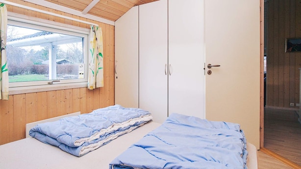 A bedroom with two beds, a window with curtains, and a wardrobe. - Cozy Holiday Home in AsnÃ¦s near Fishing (Asnaes)