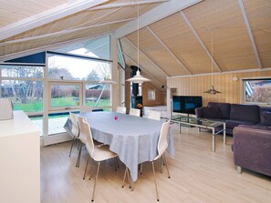 A spacious living area with a dining table, white chairs, a purple sofa, and a TV. - Cozy Holiday Home in AsnÃ¦s near Fishing (Asnaes)