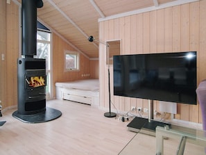 Quarto moderno com lareira a lenha, uma cama, uma TV e uma mesa de vidro.