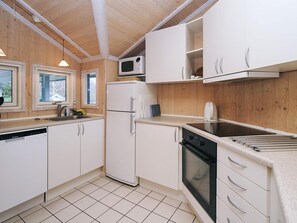 A compact kitchen with white cabinets, a microwave, a refrigerator, a sink, and a stove. - Cozy Holiday Home in AsnÃ¦s near Fishing (Asnaes)