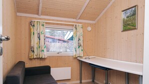 A small room with a wooden interior, a window with curtains, a table, and a sofa. - Cozy Holiday Home in AsnÃ¦s near Fishing (Asnaes)