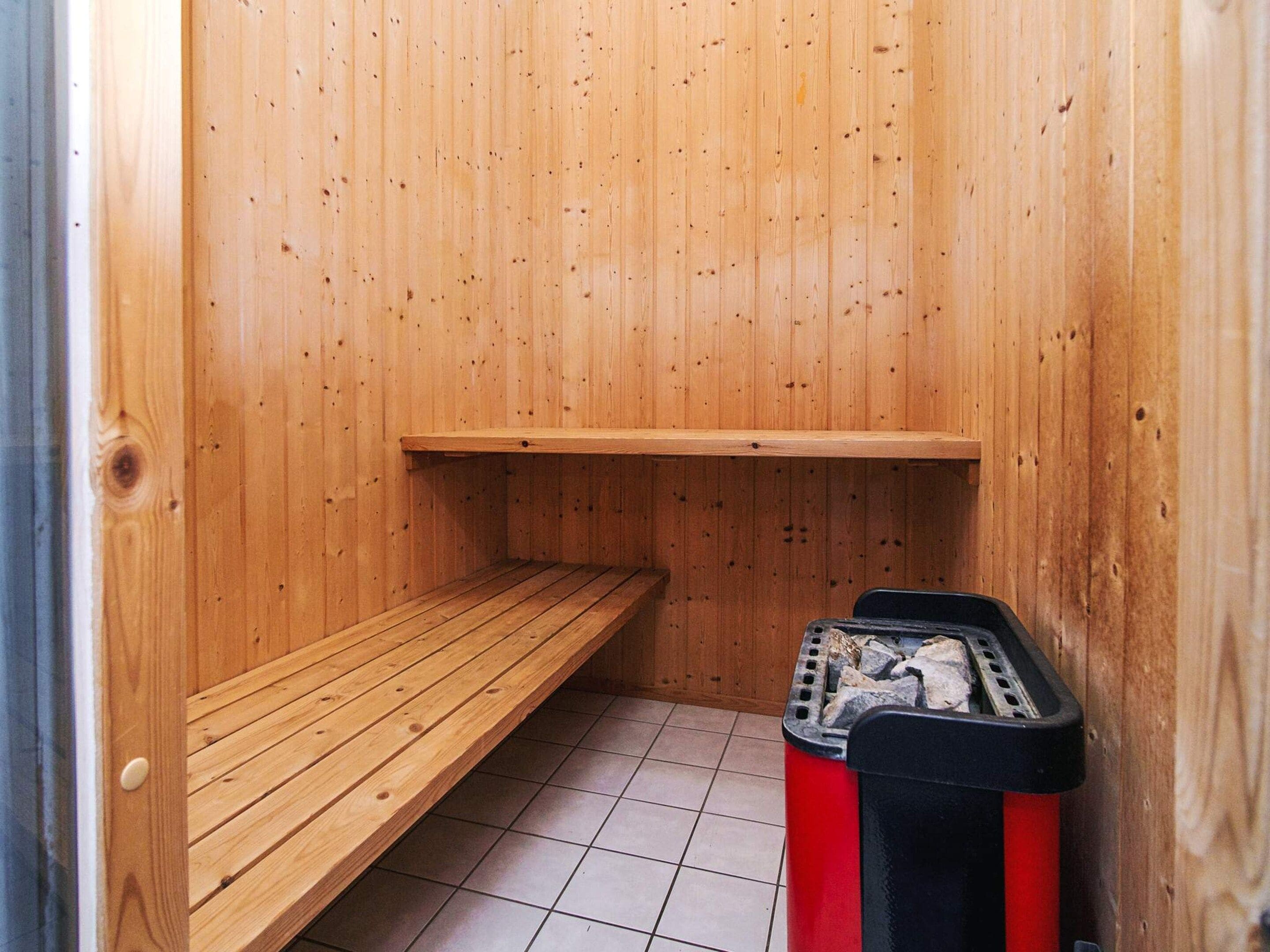 A sauna room with wooden walls, a bench, and a sauna unit.