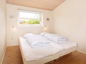 Une chambre avec un lit simple, deux lampes de chevet, une fenêtre et un plafond en bois.
