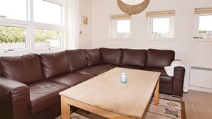A modern living room with a brown leather sectional sofa, a wooden coffee table, and a woven light fixture. - 4 Star Holiday Home in Hemmet (Hemmet)