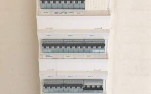 Un tableau électrique fixé au mur, équipé de plusieurs disjoncteurs.