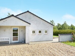 Un bâtiment d’un seul étage, à la façade blanche, avec une porte portant le numéro 34 et un petit banc à l’extérieur.