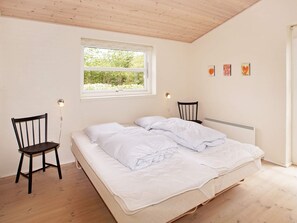 Une chambre à coucher avec un lit, deux chaises, une fenêtre et un radiateur.