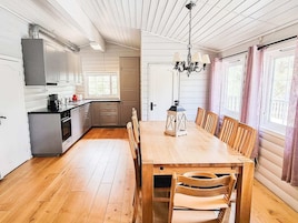 Una cocina con armarios de madera, una mesa de comedor con sillas y una lámpara de araña.
