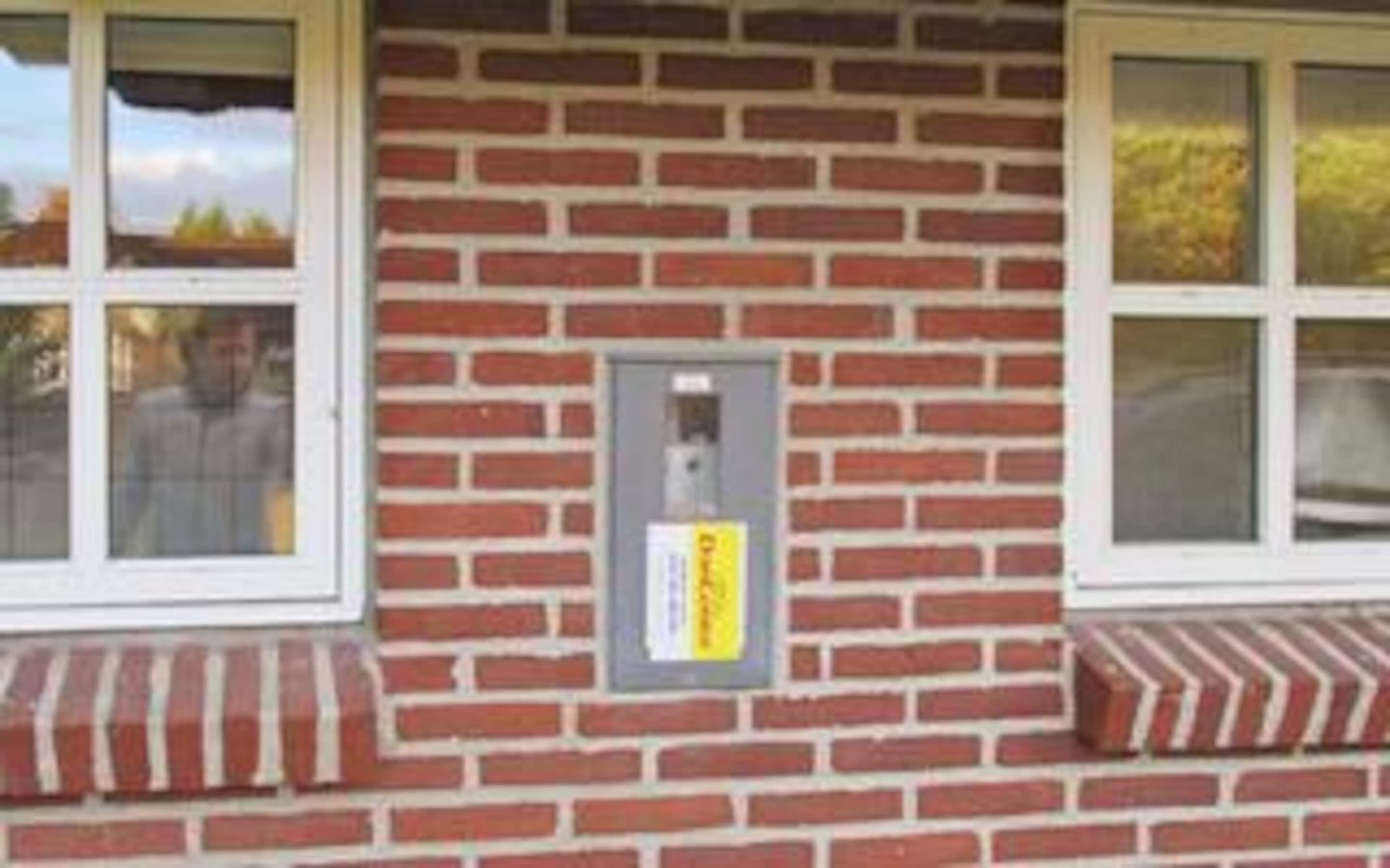Un bâtiment en briques avec une fenêtre, une porte et une petite enseigne sur le mur.