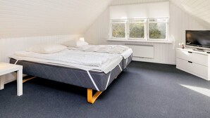 A bedroom with a bed, a TV, a window, and a radiator.