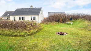 A house with a sloped roof, a front yard with a fire pit, and a bench. - 6 Person Holiday Home in Harboore (Harboore)