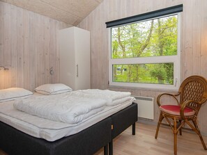 A bedroom with a bed, a chair, and a window with a view of trees. - 5 Star Holiday Home in Glesborg (Glesborg)