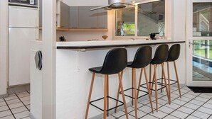 Una cocina moderna con una isla central, taburetes de bar, un microondas y una campana extractora de acero inoxidable.