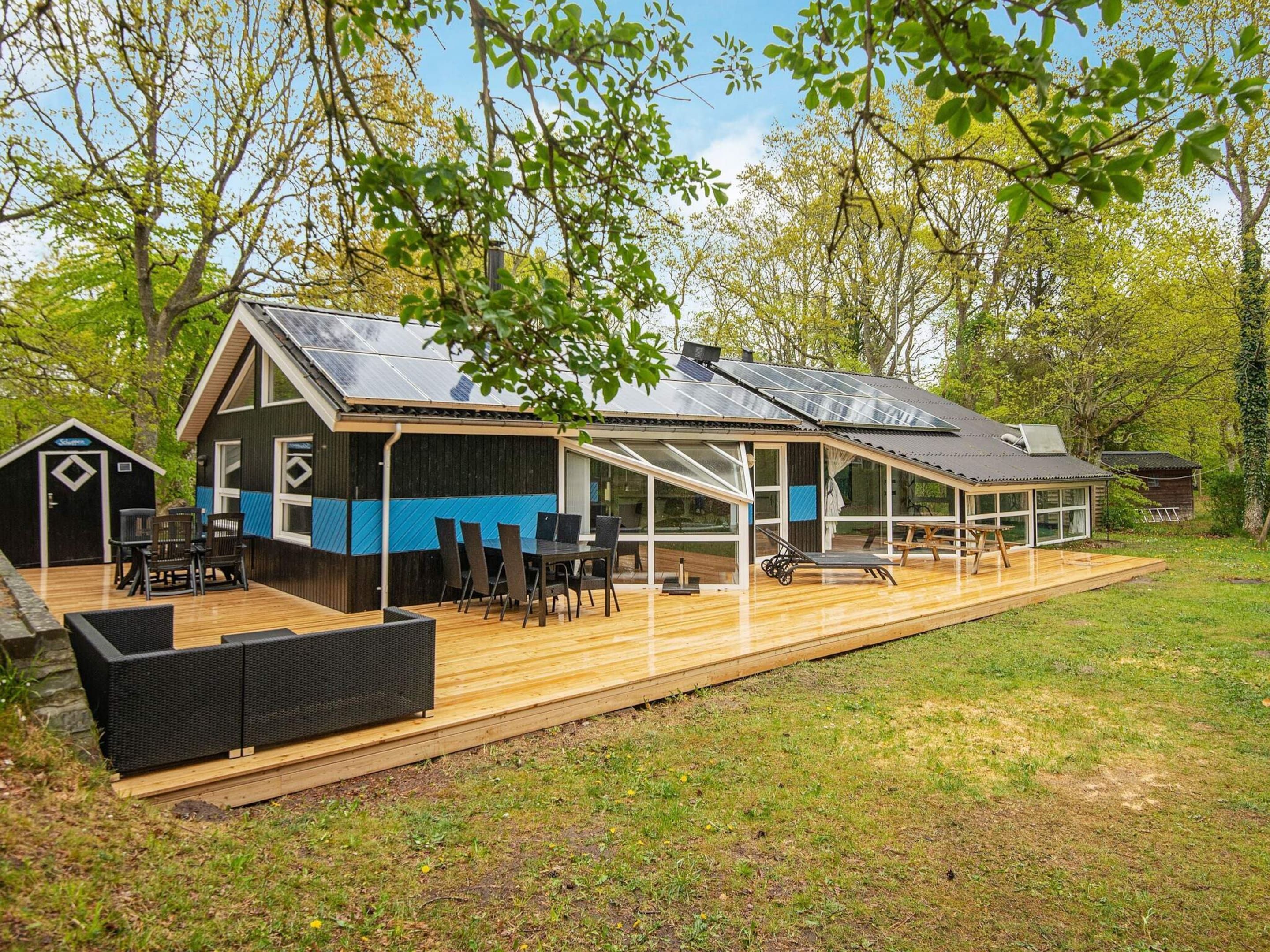 A modern house with a deck, a covered patio, and a small shed.