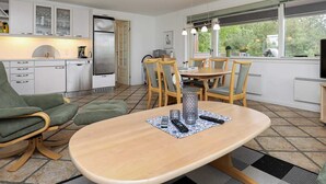 Eine moderne Küche mit weißen Schränken, einem eingebauten Kühlschrank und einem Essbereich mit Holztisch und Stühlen.