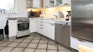 Eine moderne Küche mit weißen Schränken, einem Edelstahl-Kühlschrank, einer Spülmaschine und einem Herd.