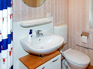 A bathroom with a white sink, a mirror above it, a toilet, and a wooden cabinet below the sink.
