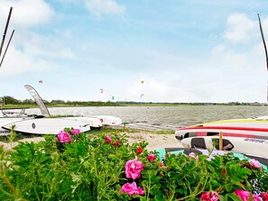 Vista de un lago con barcos y gente practicando kitesurf.
