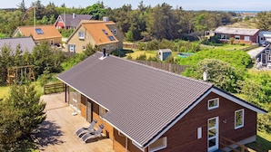 Et moderne hus med skråt tag, træterrasse og en indhegnet have.