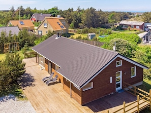 A modern house with a sloped roof, a wooden deck, and a fenced yard.