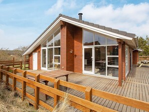 A wooden cabin with large windows, a deck, and a chimney. - 5 Star Holiday Home in Thisted (Thisted)