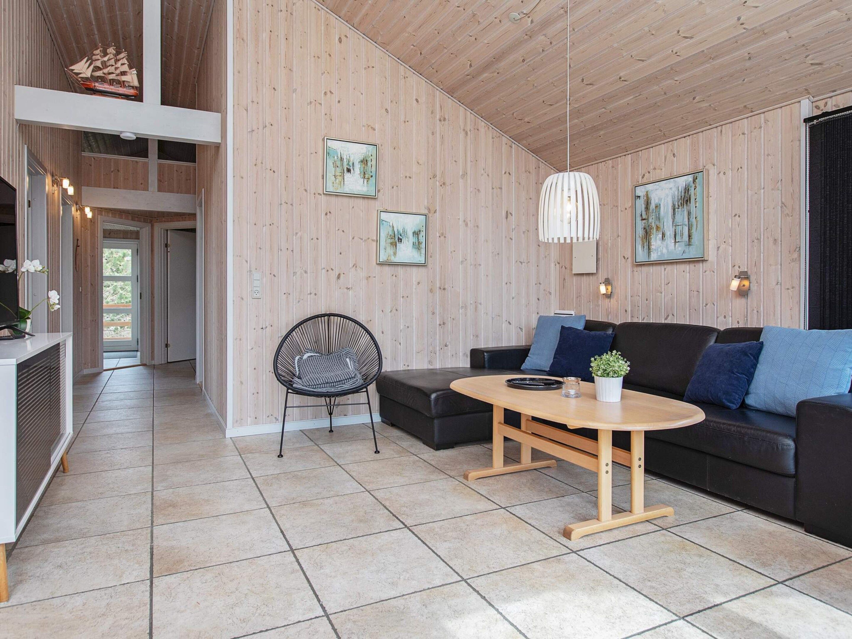 Ein modernes Interieur mit Holzbalkendecke, einer Couch, einem Esstisch und einem Stuhl.