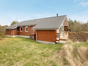 A single-story wooden house with a tiled roof, a front porch, and a small attached garage.