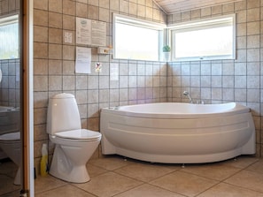 A bathroom with a toilet, a bathtub, and tiled walls. - 5 Star Holiday Home in Thisted (Thisted)
