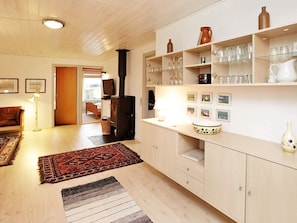 A cozy kitchen with wooden cabinets, a black stove, and various glassware on shelves.