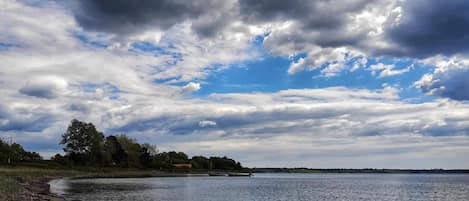 A calm body of water with a sandy beach and a line of trees in the distance.