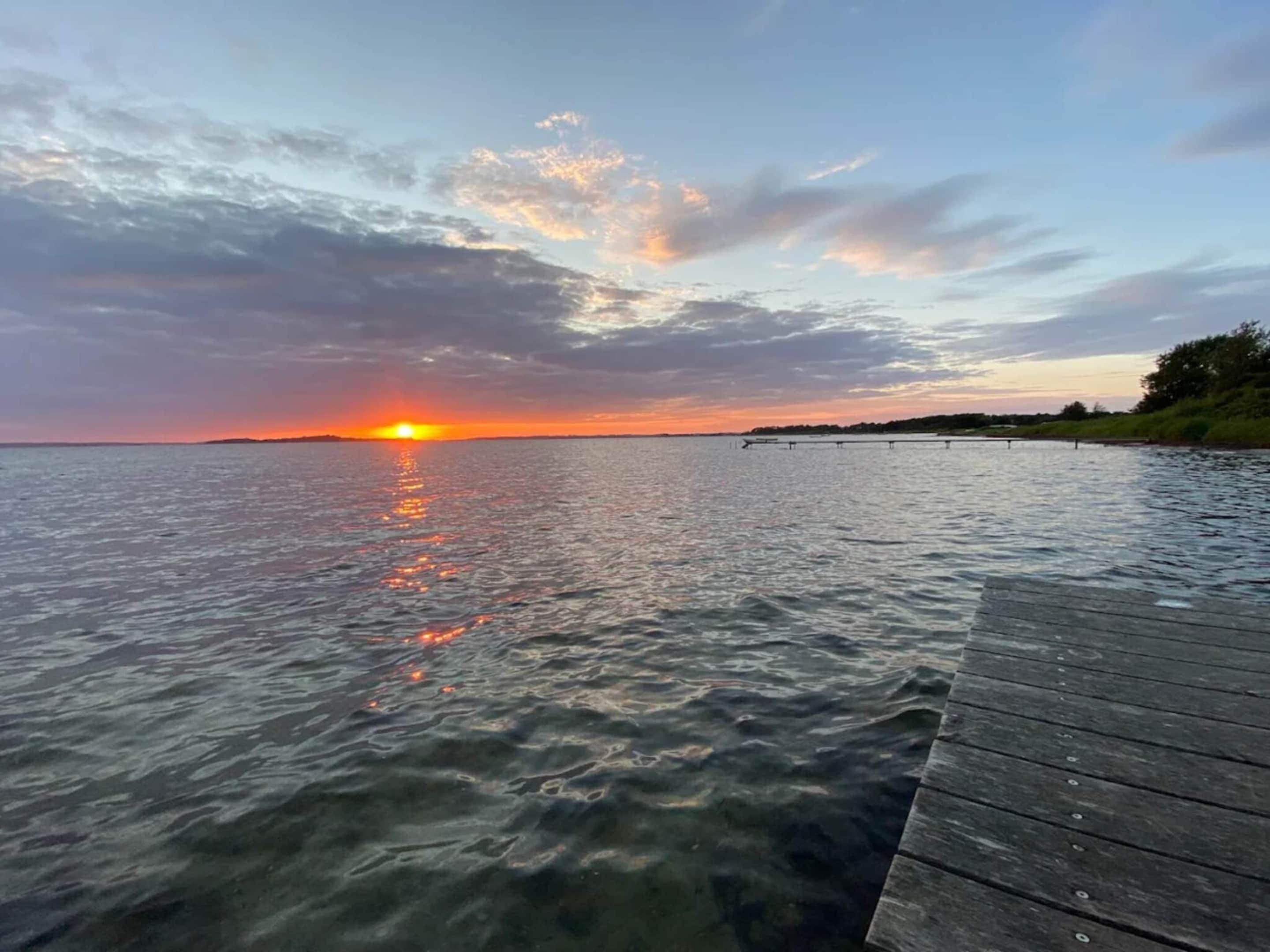 A sunset over a body of water with a wooden dock extending into the water.