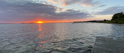 A sunset over a body of water with a wooden dock extending into the water.