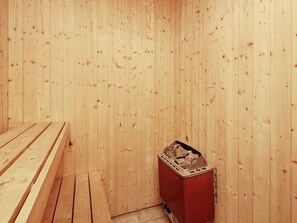 A sauna room with wooden benches and a portable heater. - 6 Person Holiday Home in Millinge (Millinge)