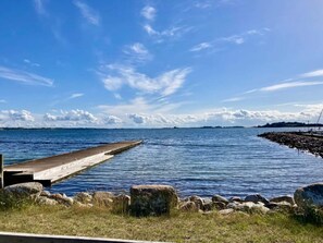 A pier extending into calm waters with a clear sky and distant land. - 6 Person Holiday Home in Millinge (Millinge)