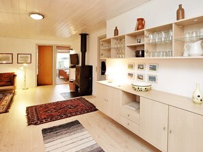 A cozy kitchen with wooden cabinets, a stove, and a dining area with a sofa and rugs. - 6 Person Holiday Home in Millinge (Millinge)