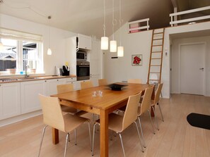A modern kitchen with white cabinets, a dining table with chairs, and pendant lighting. - 5 Star Holiday Home in Nysted (Nysted)