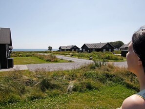 A coastal area with several wooden houses, a gravel path, and a view of the sea.