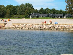 A lakeside resort with multiple cabins, a sandy beach, and a rocky shoreline.