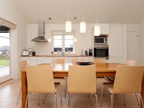 A modern kitchen with a dining table, chairs, and pendant lights. - 5 Star Holiday Home in Nysted (Nysted)