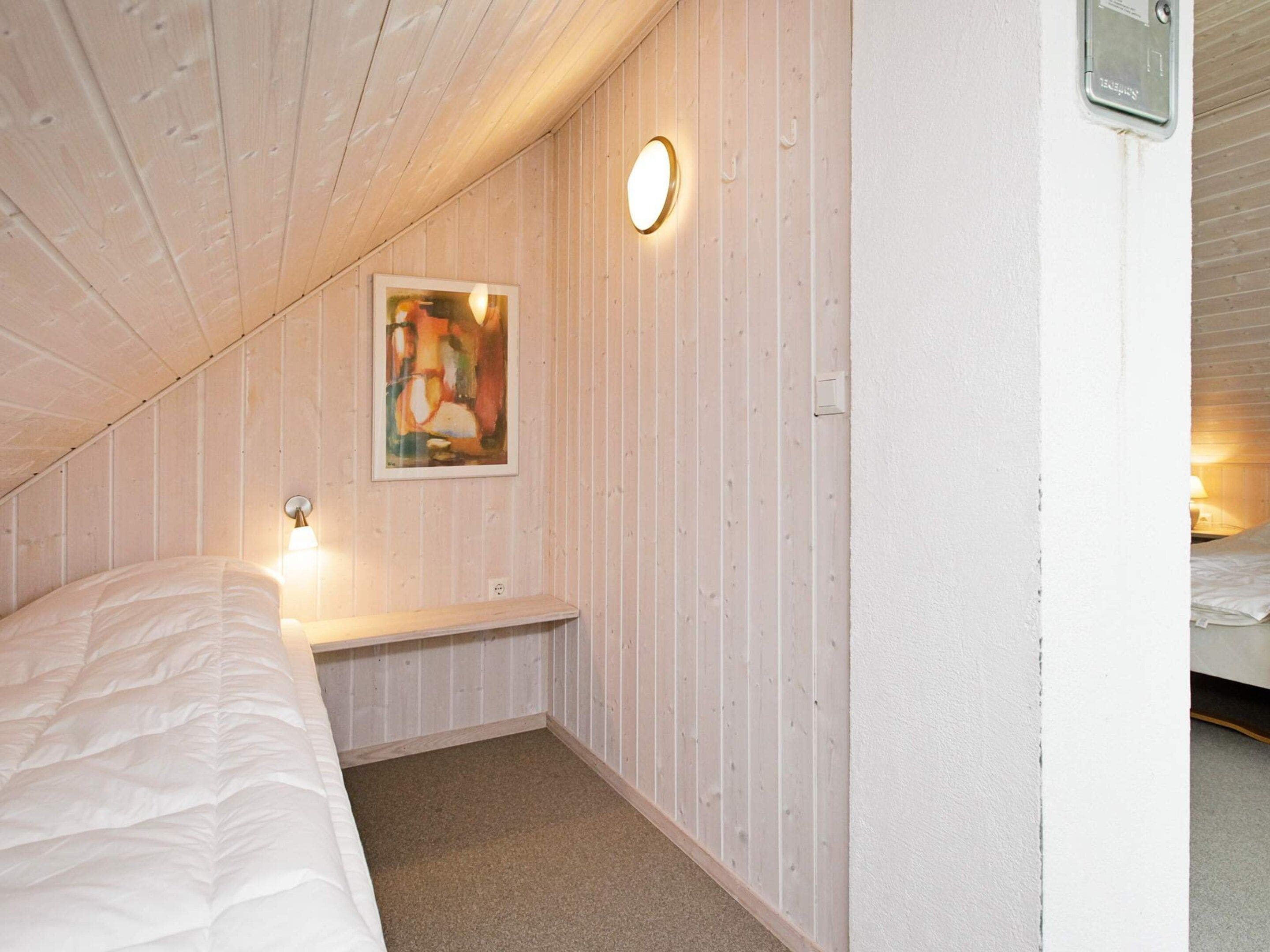 Ein Schlafzimmer mit einem Bett, einem Nachttisch, einer Wandleuchte und einem Gem älde.