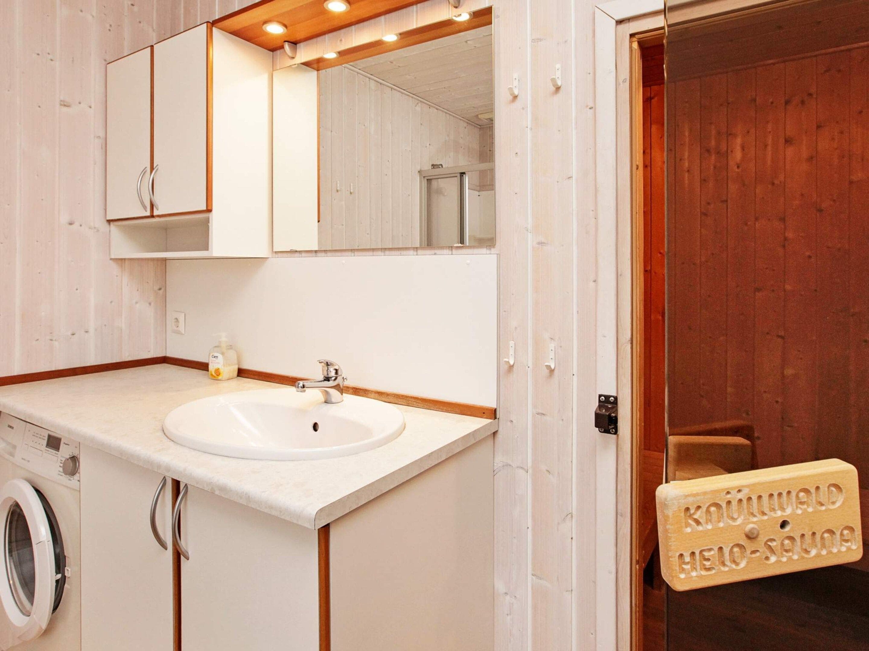 Une salle de bain avec une porte en bois, un lavabo, un miroir et un lave-linge.
