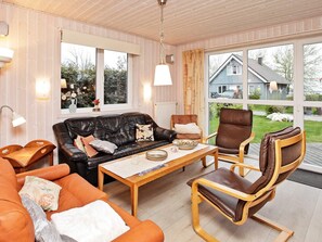 Un salon chaleureux avec un canapé en cuir, un fauteuil orange, une table basse en bois et un fauteuil en cuir marron.