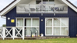 A two-story house with a balcony, large windows, and a fenced front yard.