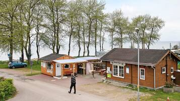 A wooden building with a sign reading 'Kiosk' and a man walking on a paved path.