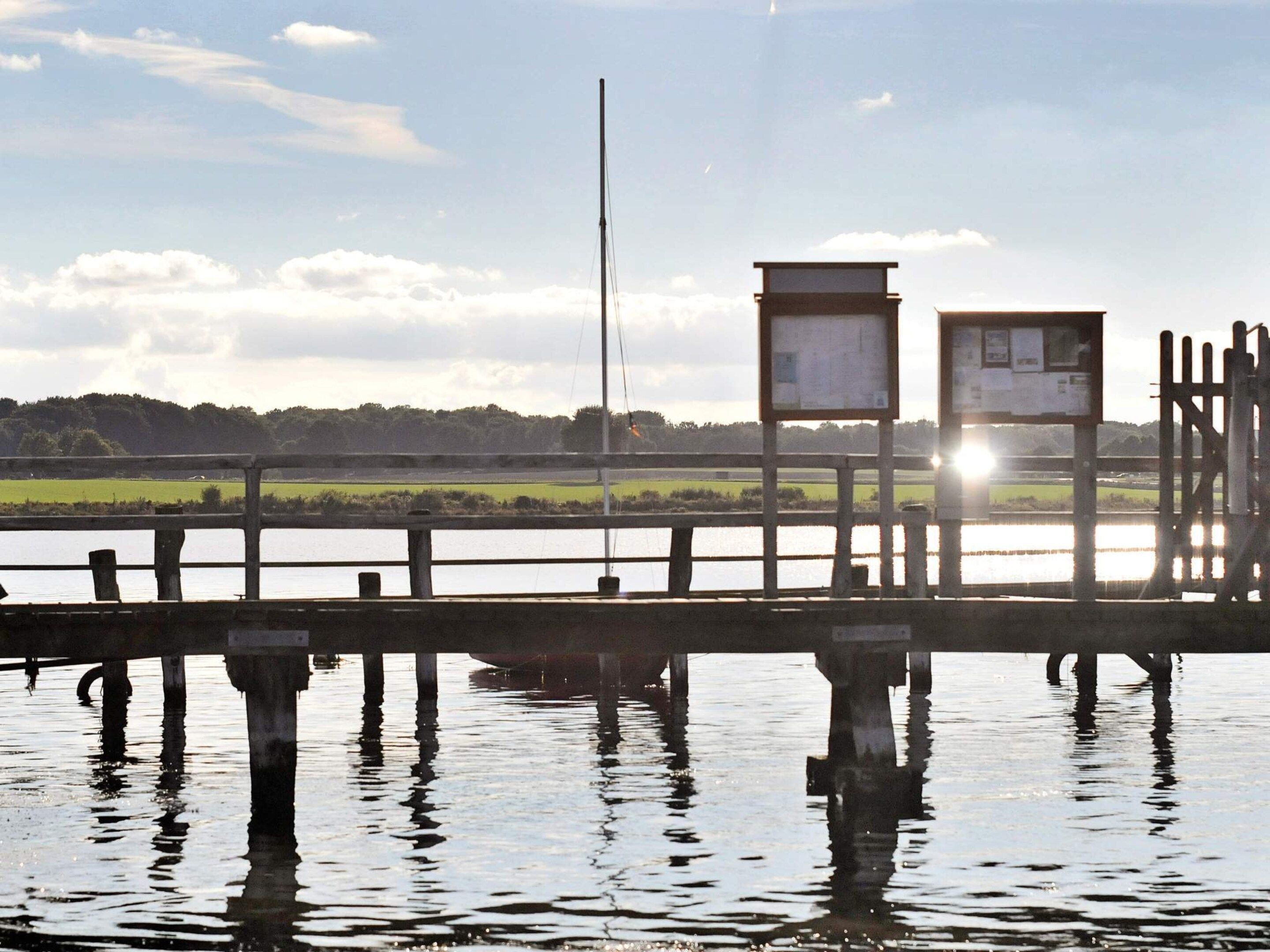 A wooden pier extending into a body of water with a clear sky above.