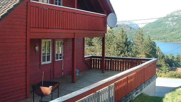 A red wooden house with a balcony, a satellite dish, and a view of a lake and mountains. - 27 Person Holiday Home in Dyrdal-by Traum (Gjesdal)