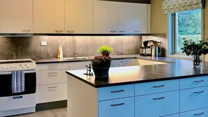 A modern kitchen with white cabinets, a central island, and a window with a view of greenery. - 27 Person Holiday Home in Dyrdal-by Traum (Gjesdal)