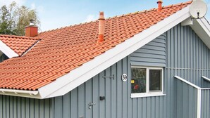 Un bâtiment gris avec un toit recouvert de tuiles rouges, une antenne parabolique et une fenêtre sur laquelle est inscrit le chiffre « 59 ».
