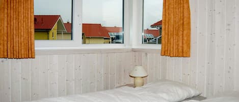 A bedroom with a bed, a window, and a lamp.